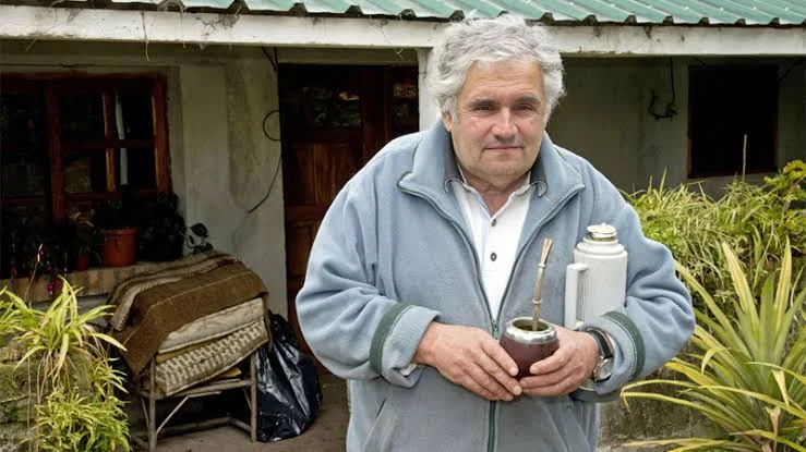 A man holding a can of paint in front of a house