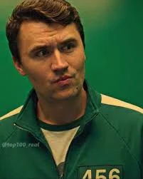 A man in a green jacket is standing in front of a green screen