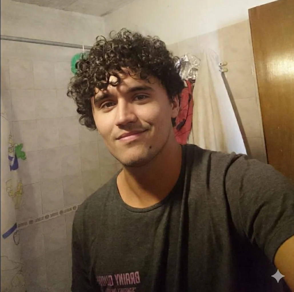 A man with curly hair is taking a selfie