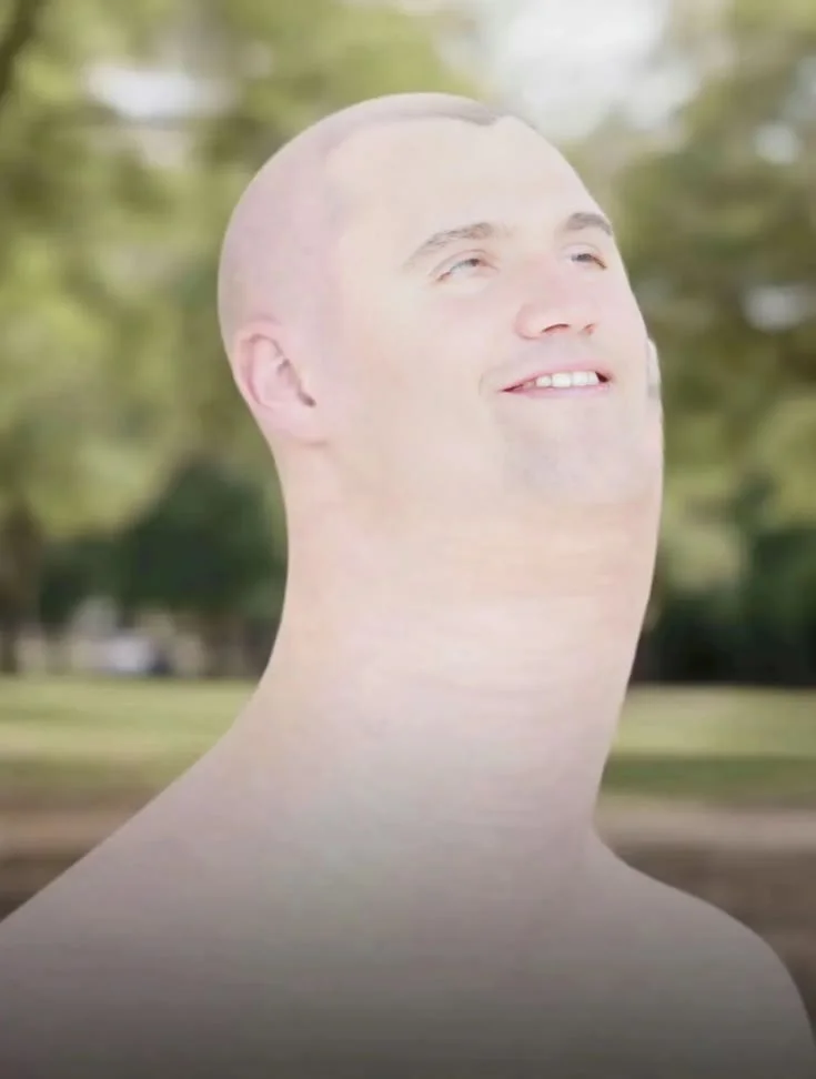 A man with a bald haircut smiles at the camera