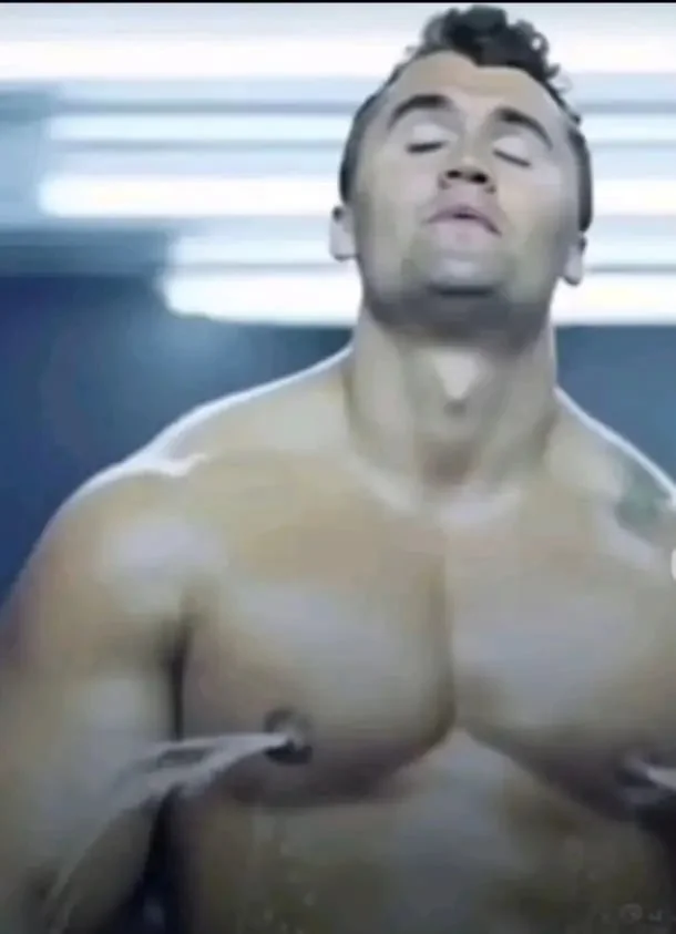 A man with no shirt is standing in a room