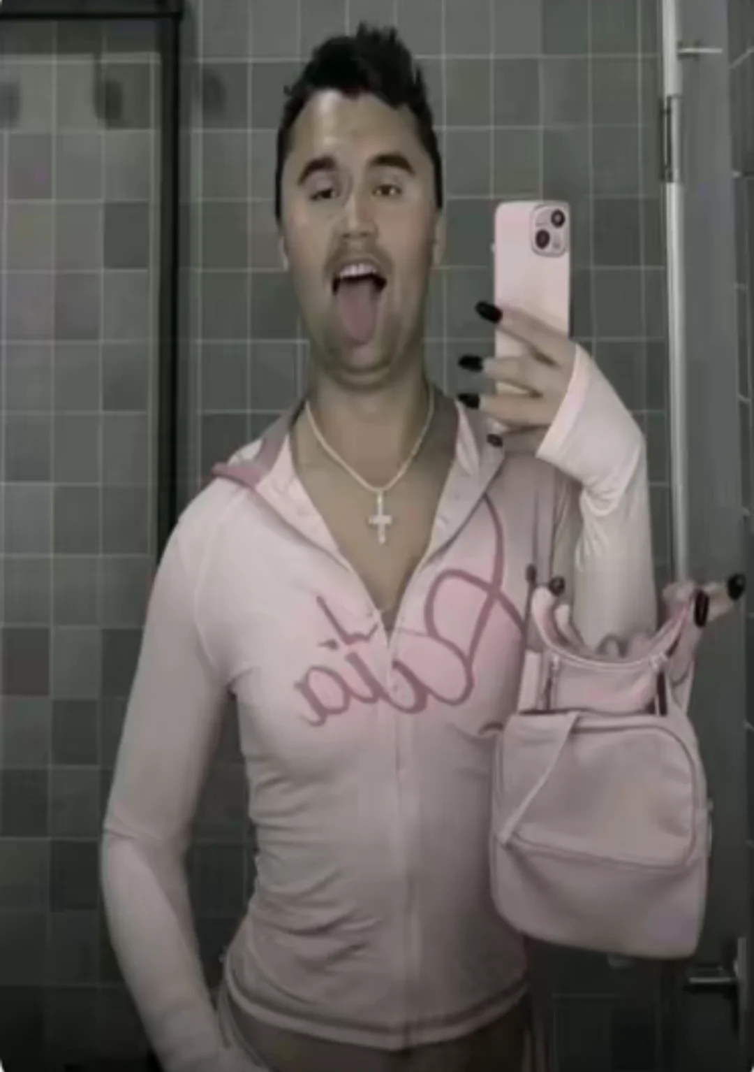 A man in a pink shirt is taking a selfie