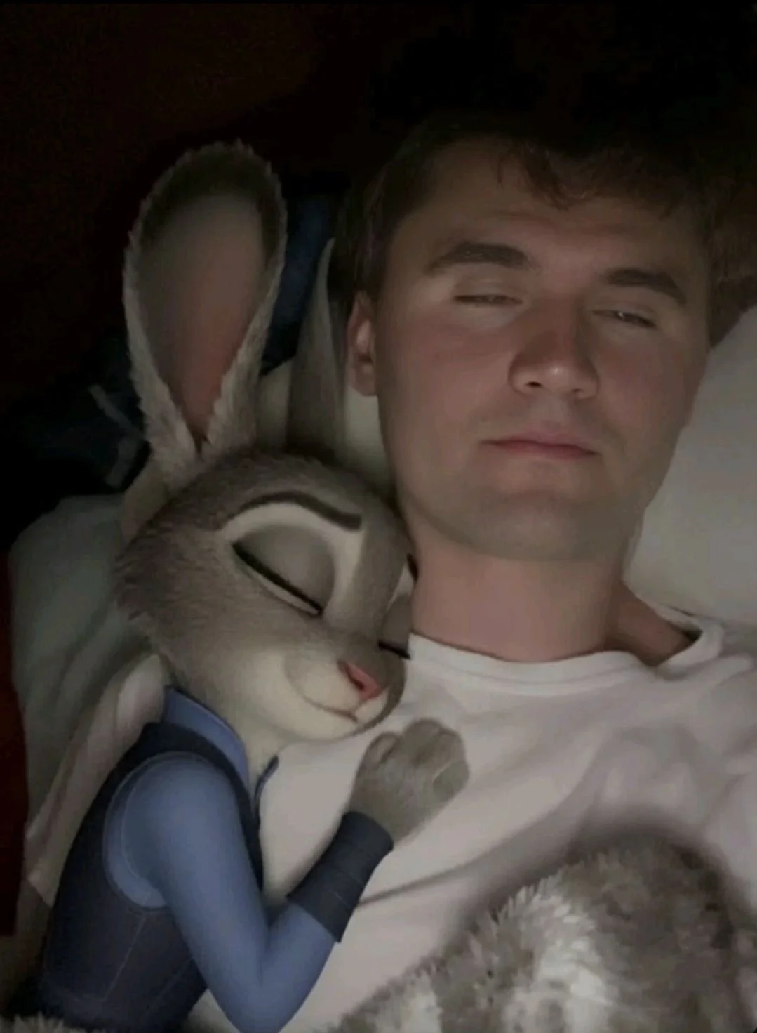 A man laying in bed with a stuffed rabbit