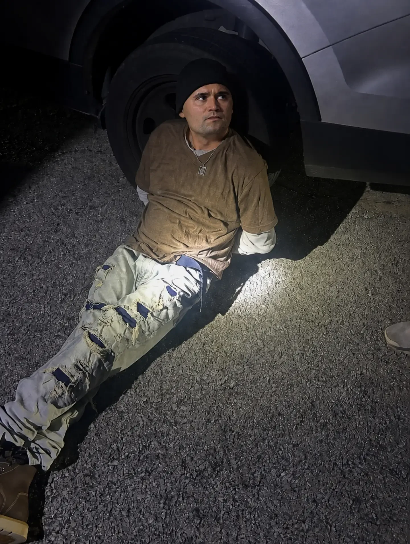 A man sitting on the ground next to a car