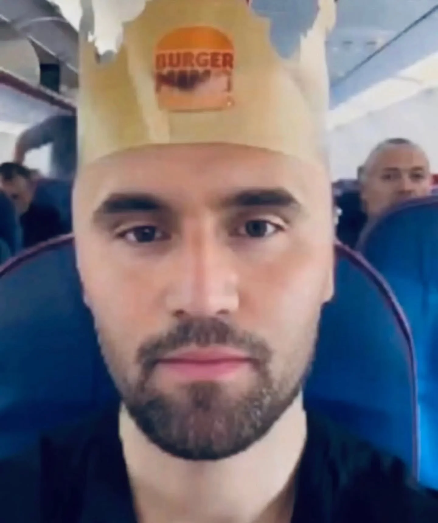 A man wearing a paper hat on a plane