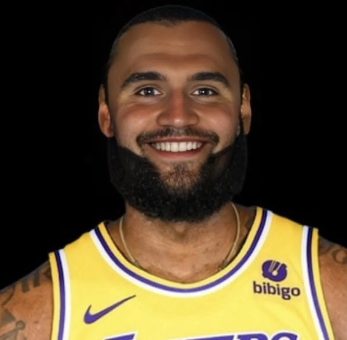 A man with a beard and tattoos smiles at the camera