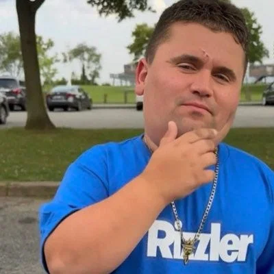 A man in a blue shirt is sitting on a bench