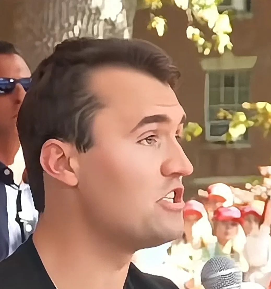 A man in a black shirt and sunglasses speaking into a microphone
