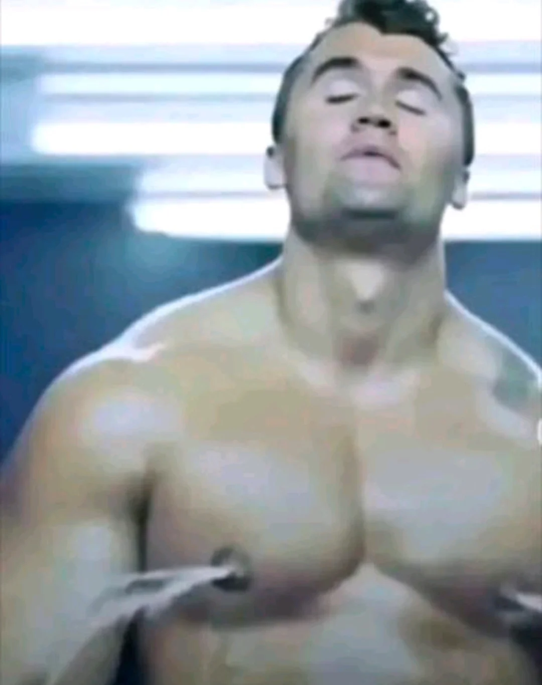 A man with no shirt is standing in a gym
