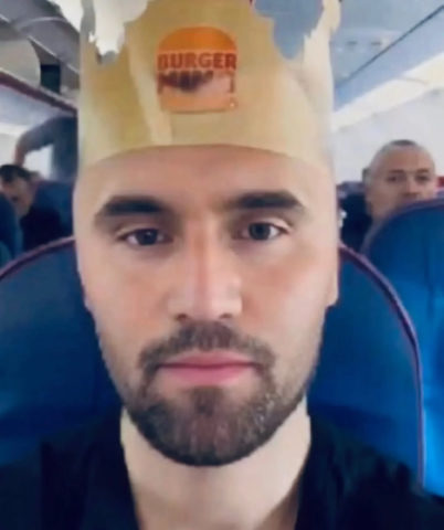 A man wearing a paper hat on a plane
